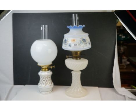 An antique oil lamp with opaque base and floral decorated shade and chimney together with one other with floral decorated bas
