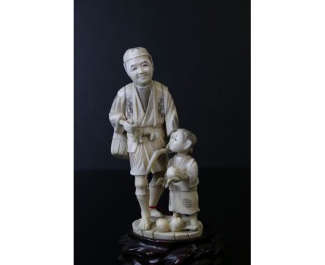 A Japanese carved ivory sectional okimono of a farmer and son, the man holding an axe in his left hand and another tool (brok