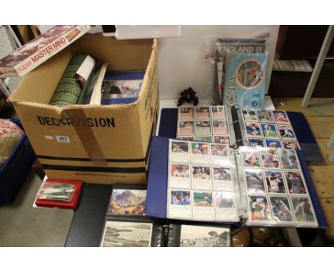 A box of mixed collectables to include trading cards, postcards, vintage games and jigsaws. 