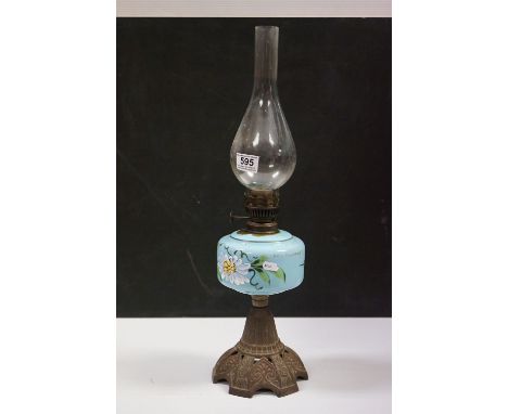 An early 20th century cast iron based oil lamp with floral painted blue well and glass chimney. 