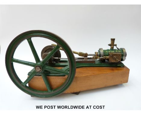 A horizontal stationary live steam engine mounted on a wooden base with 26cm diameter flywheel and cyclinder with lubricator