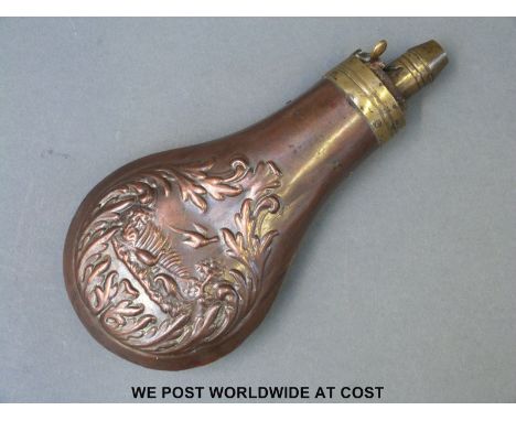 Copper powder flask with embossed decoration in the form of birds amongst foliage and brass mount.  