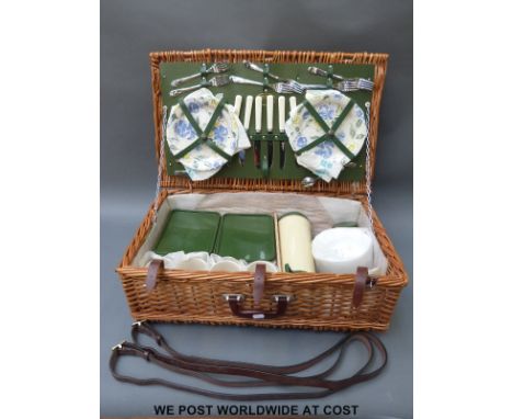 A retro picnic hamper with china plates, metal cutlery, thermos, leather straps etc.