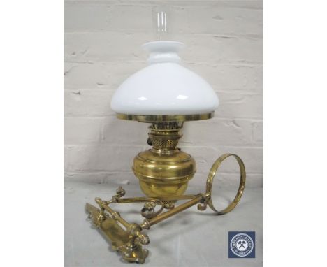 A Victorian brass wall-mountable oil lamp with bracket, glass chimney and white shade