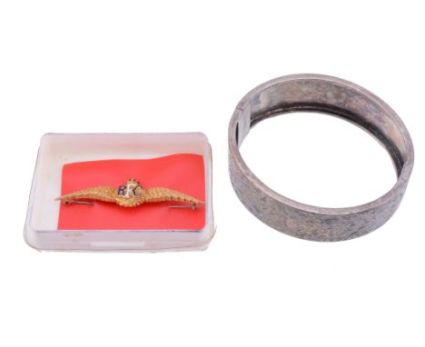  A bangle,   the hinged bangle with foliate engraving, to a concealed clasp, 5.7cm inner diameter; together with a brooch 
