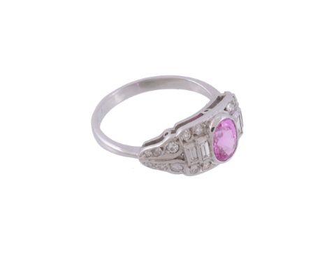  A pink sapphire and diamond ring,   the central oval shaped pink sapphire collet set within a surround of baguette cut and b