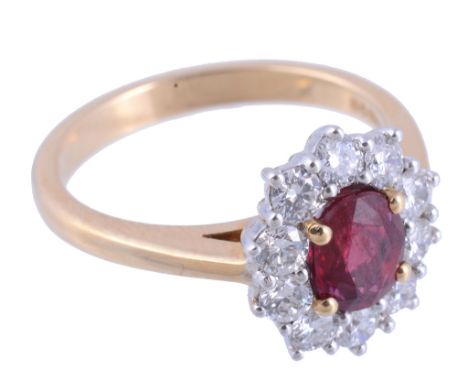 A ruby and diamond cluster ring,   the central oval shaped ruby in a four claw setting within a surround of brilliant cut di