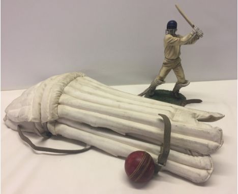 Comprising: A modern Leonardo Collection figurine, a cricket ball, and a pair of vintage cricket pods. 