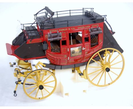 A Franklin Mint 1/16 scale boxed diecast model of a Wells Fargo Stage Coach finished in black, red and yellow, in the origina