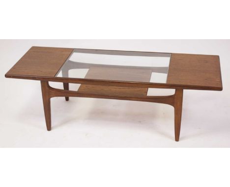 A 1960s G-Plan teak rectangular coffee table, having clear glass inset top surface over a platform undertier to tapering supp