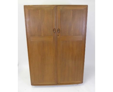 An Ercol light elm double door compactum wardrobe, the interior with hanging rails and integral bank of four graduated drawer