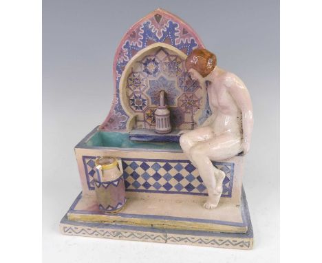 J.E. Tindall - a circa 1930 ceramic figural study in the Moroccan taste, modelled as a seated nude bather beside an ornamenta