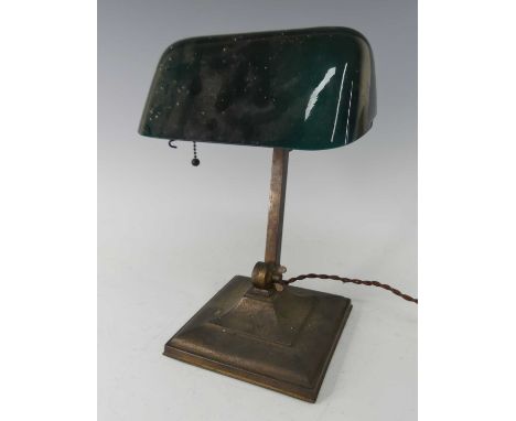 A 1930s American brass bankers desk lamp by Emeralite, with green glass domed adjustable shade, raised on square base, h.32cm