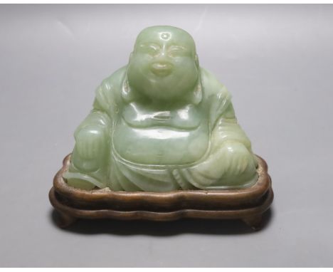   A Chinese carved bowenite jade figure of a seated Budai, H 9cm, W 13cm on carved wooden stand