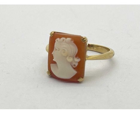 A Carved Shell Cameo Rectangular Panel Ring, the carved portrait of a lady to four claw set, between tapered shoulders stampe
