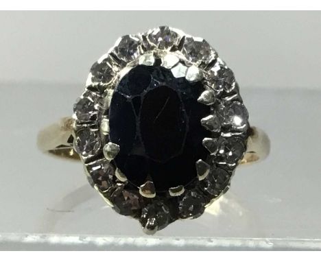 NINE CARAT GOLD RING,set with sapphire in a surround of diamond chips