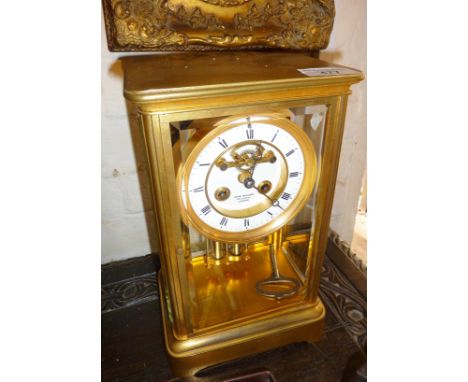 A brass four-glass mantel clock with enamel dial and visible escapement. The movement striking on a bell and having a mercury