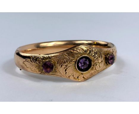 A Victorian gold plated bangle with 3 amethyst coloured stones in acanthus setting 
