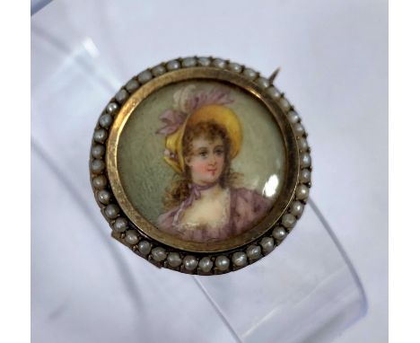 A brooch with half length miniature portrait of a young woman in a bonnet, bordered by seed pearls, with safety chain, diamet