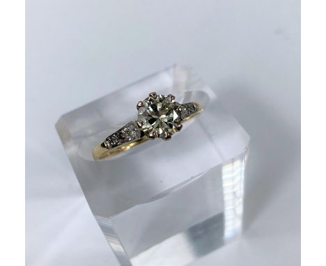 A yellow metal ring set diamond solitaire stone of 1.10 metric carat approx, each shoulder set 3 small diamonds, unmarked tes