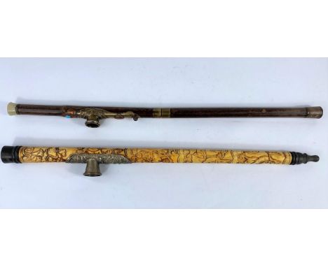 A Chinese brass mounted opium pipe, 48 cm; another in carved bone, 47 cm.&nbsp; Generally good condition for age, bone pipe h