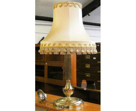 A brass effect column table lamp with gold fringed tasseled shade. 