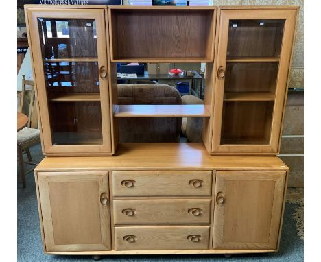 An Ercol beech wall unit 156 x 162 cm, the top with display shelves to either side behind glazed doors and open shelf center,