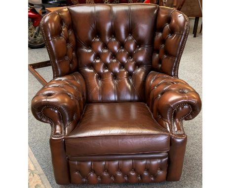 A brown leather button back wing armchair (matches lot 288). 