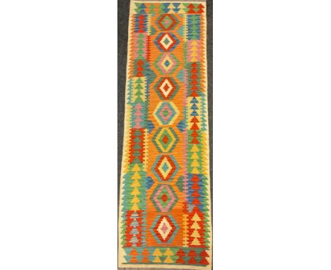 A Turkish Anatolian Kilim runner carpet, knotted with a central row of nine diamond-shaped medallions, in bright colours, ora