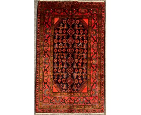 A North west Persian Hamadan rug / carpet, hand-knotted in deep tones of red, brown, and blue, on a black ground, the central