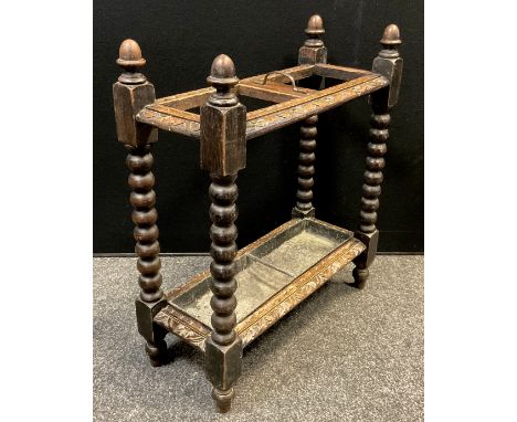 An early 20th century carved oak umbrella /stick stand, two section top, turned columns terminating with acorn finials, lift-