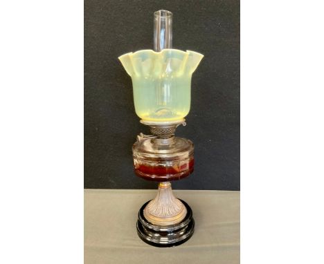 A Victorian oil lamp, with Vaseline yellow/green Uranium glass shade, above clear reservoir and brass base. 