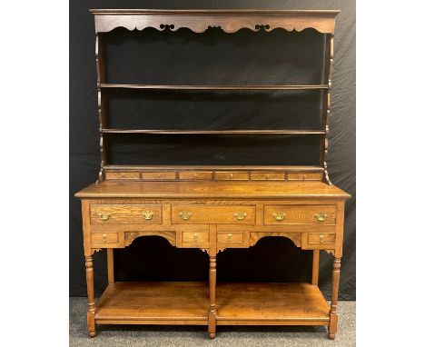 An Elm Welsh dresser, plate-rack top with moulded cornice, shaped apron, three tiers of shelving and row of six small spice d
