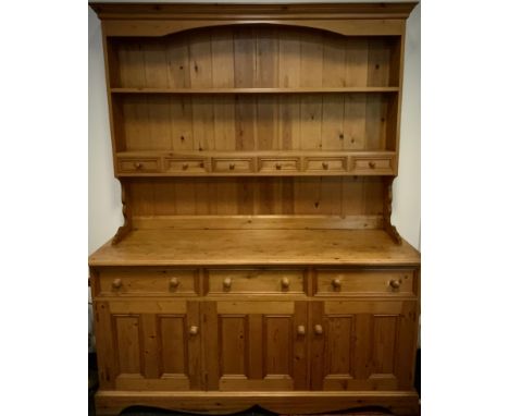 A pine dresser, plate rack top with central row of six spice drawers, over a base with three short drawers, and three cupboar