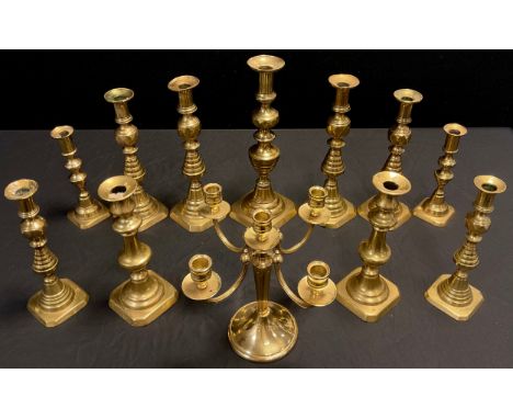 Three graduated pairs of brass candlesticks, ribbed pyramidal stems, canted square bases, the largest pair 30cm high;  anothe
