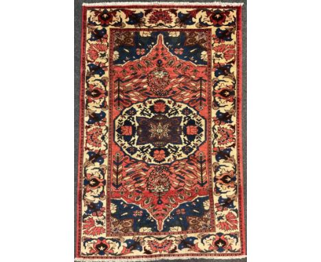 A central Persian Bakhtiar rug / carpet, hand-knotted in muted tones of red, blue, and cream, 209cm x 130cm. 