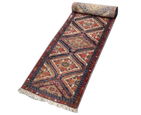 AN EASTERN NARROW RUNNER, the central pattern of ten interlinked diamond medallions within a hooked border, 410 x 62cm