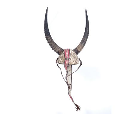 A WEST AFRICAN HORNED HELMET from the Konkomba people with plant fibre, leather and broad cloth decorated with cowrie shells,