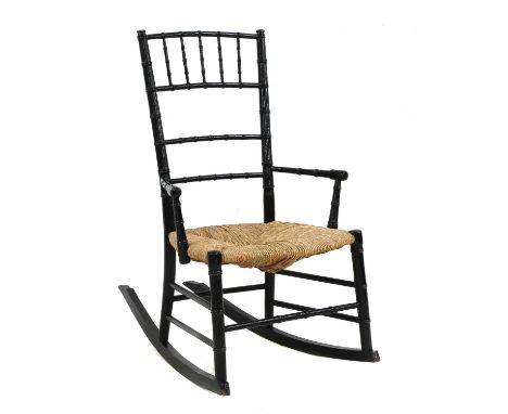 An Aesthetic ebonised child's rocking chair, after E W Godwin, with ring turned supports, a rush seat on long rails, 49cm wid