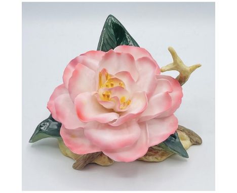 Light inner pink petals with darker pink edge, centered with yellow pistels sitting upon a base with 3 green leaves / Issued 