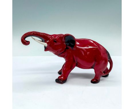 Red and black glazed porcelain figure of an elephant with trunk outstretched and curled down. White painted tusks. Royal Doul
