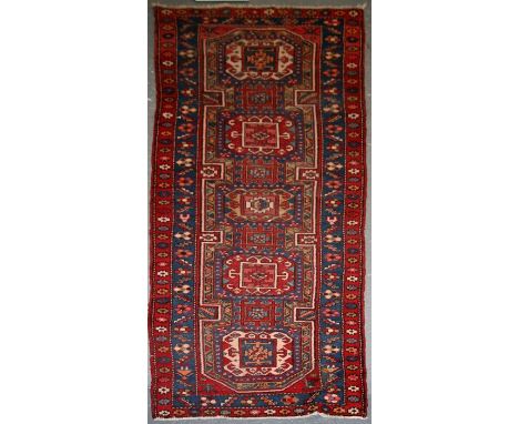 A Persian Azari hand knotted woollen runner with five stylised guls within floral borders, on a blue ground, 312 by 105cms (1