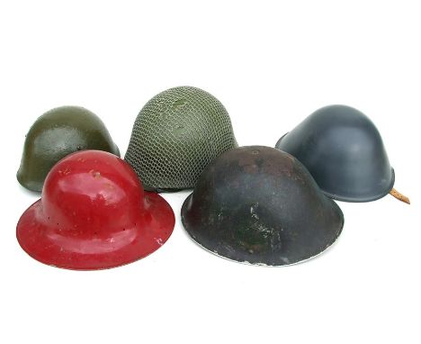 A US Army helmet with camo net; together with four similar helmets (5).