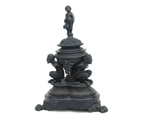 A 19th century bronze inkwell and cover, the cover surmounted with a cherub, the well supported by three satyr, 28cms high.
