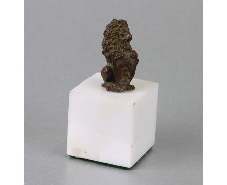 A miniature bronze figure in the form of a rampant lion holding an heraldic shield, 4cms high, on a marble plinth, overall he