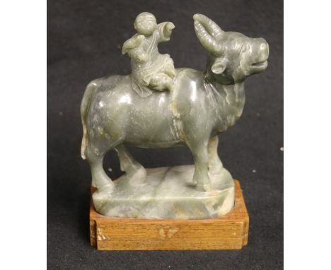 Chinese early 20th century grey green and mottled brown jade carving of a boy seated on a buffalo, a bird resting on his arm,