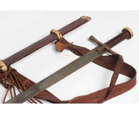 A SUDANESE KASKARA SWORD, the 34 1/2" blade etched with script and repeating designs, cruciform hilt, leather scabbard and st