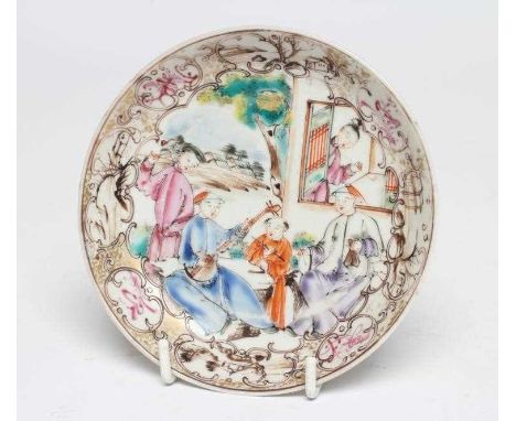 A CHINESE PORCELAIN SAUCER centrally painted in coloured enamels with a boy seated at a window overlooking musicians on a ver