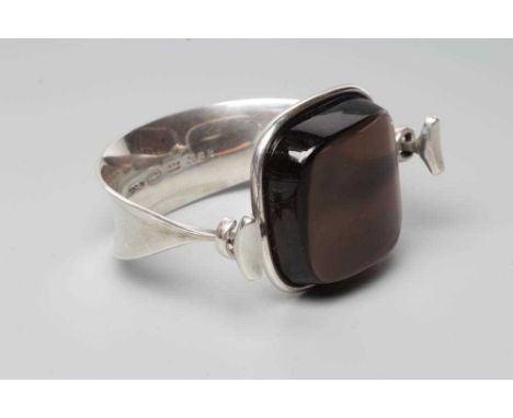 A GEORG JENSEN SILVER BANGLE designed by Viviana Torun Bulow-Hube, the tension clamp centred by a polished smoky quartz, stam