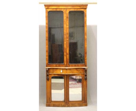 A VICTORIAN WALNUT TWO STAGE BOOKCASE, the moulded cornice over two arched glazed doors enclosing adjustable shelving, protru